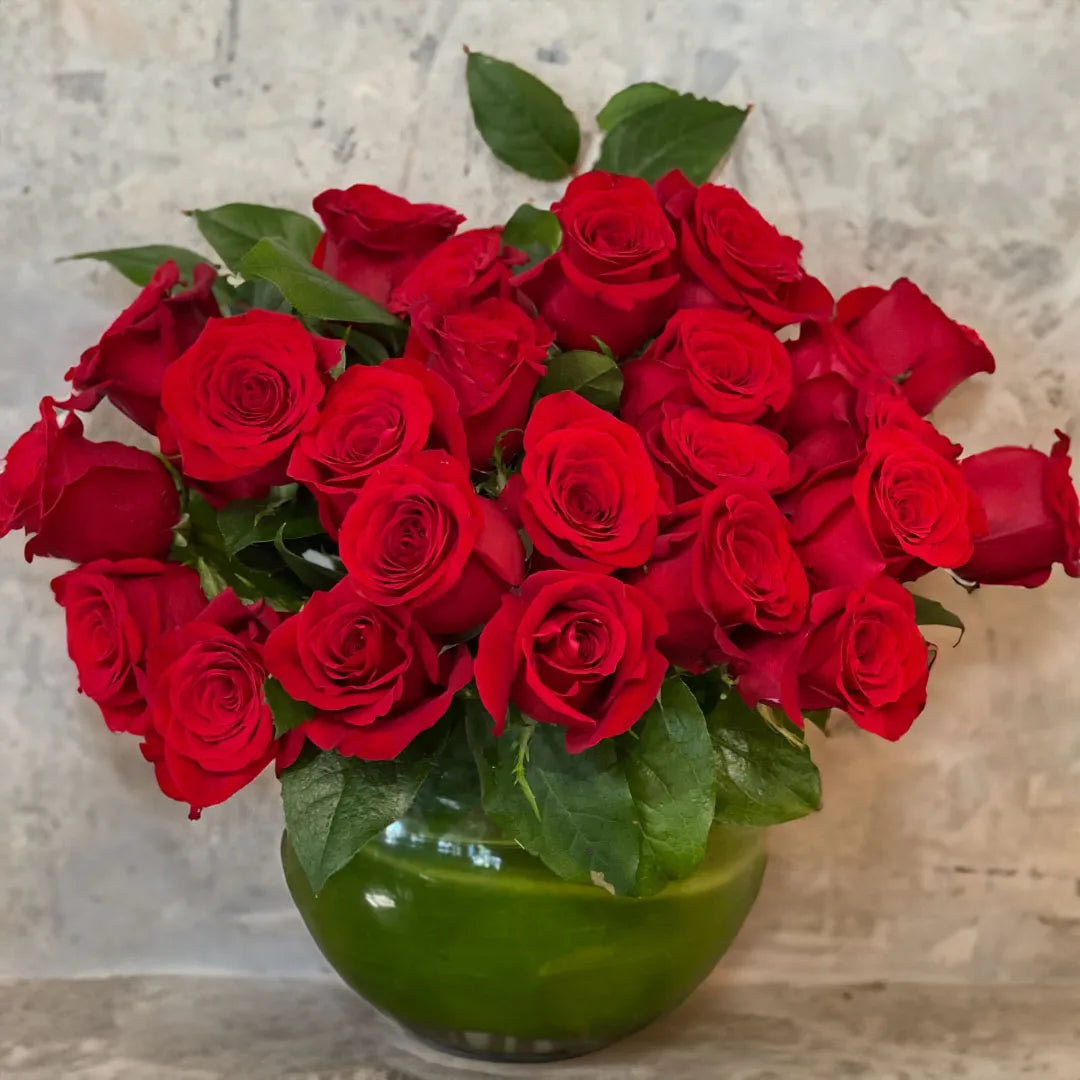 Bouquet of red roses in a green vase on a marble surface